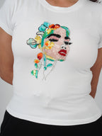 Close-up of hand-embroidered feminine portrait and floral artwork on Fleur de Femme Top