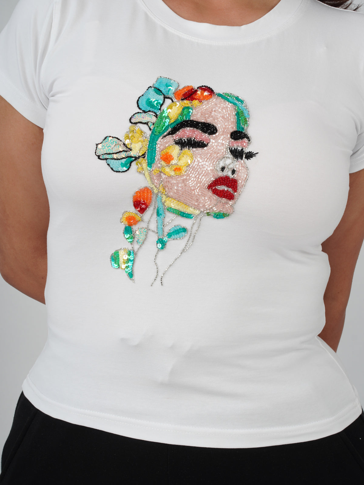 Close-up of hand-embroidered feminine portrait and floral artwork on Fleur de Femme Top