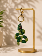 Snake charm hanging from golden-tone clasp